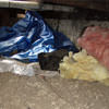A crawl space filled with loose insulation, debris, and a large tarp in Spring Valley.