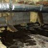 Fiberglass insulation dripping off a floor joist in a soaked crawl space with a think black liner in Cedar Rapids.