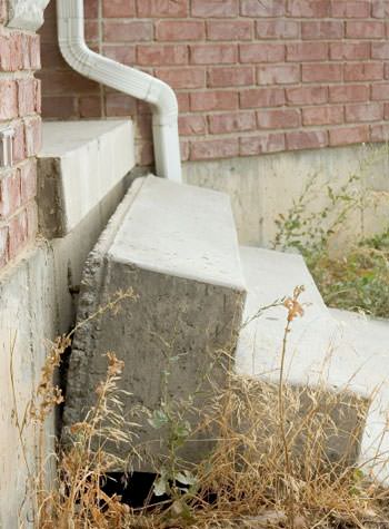 sinking outdoor concrete steps showing cracking and soil washout in East Moline