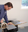 installing a waterproof vapor barrier on a basement floor to prepare for basement carpeting in a Bloomington home