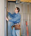 Insulated basement wall panels being placed against a concrete foundation wall in Normal